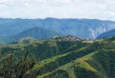Small village nestled in the middle of a lush green valley surrounded by rolling hills and trees