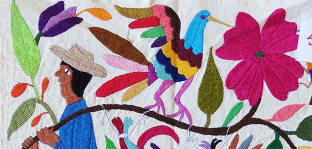 Close up of a quilted wall hanging with a woman and a bird on it