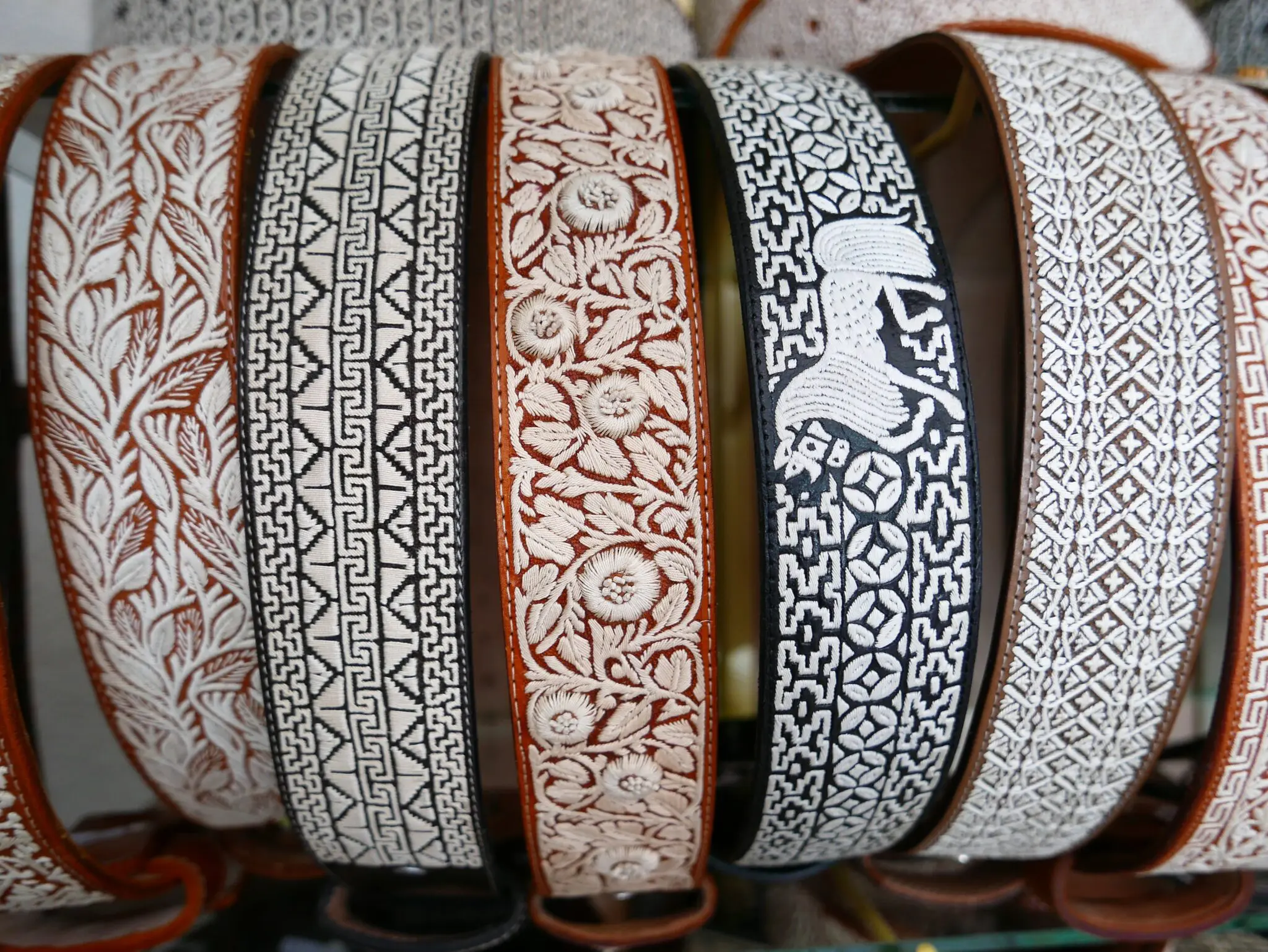Table with a variety of belts of different colors and designs, including white, black, and brown