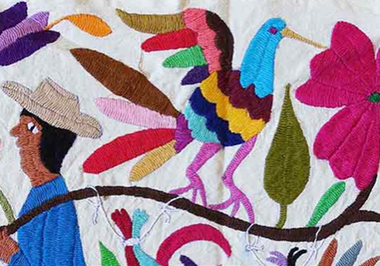 Close up of a quilted wall hanging with a woman and a bird on it