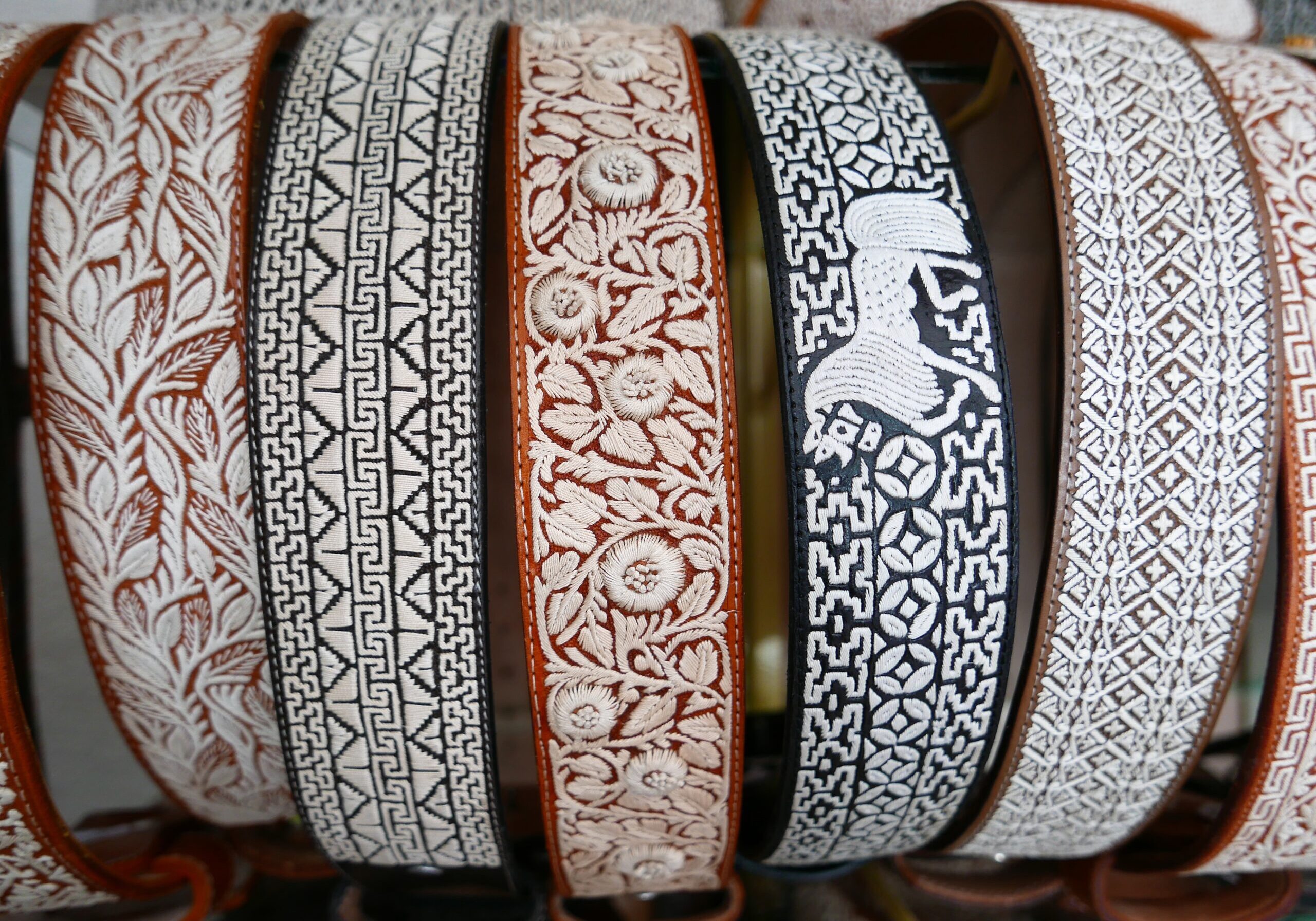 Table with a variety of belts of different colors and designs, including white, black, and brown