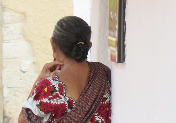 Woman in a sari leaning against a wall, with a frame attached to the wall